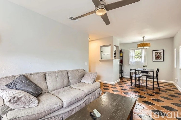 A living room with a couch, a coffee table, and a ceiling fan.