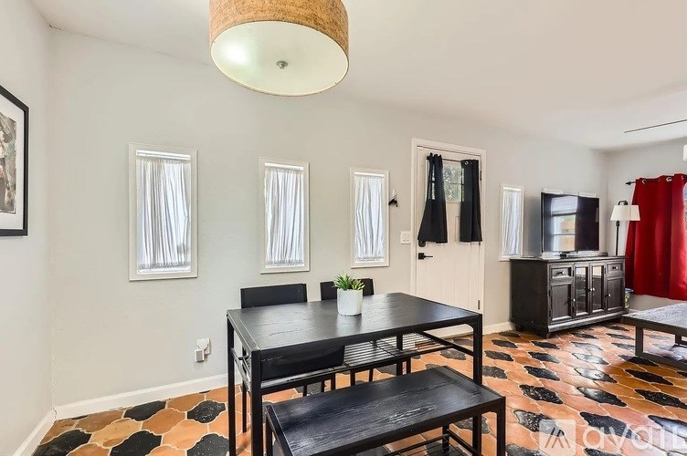 A dining room with a black table and chairs.