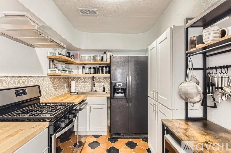 A kitchen with a black fridge and a black and white tiled floor.