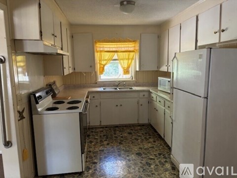A kitchen with white cabinets and a tiled floor.