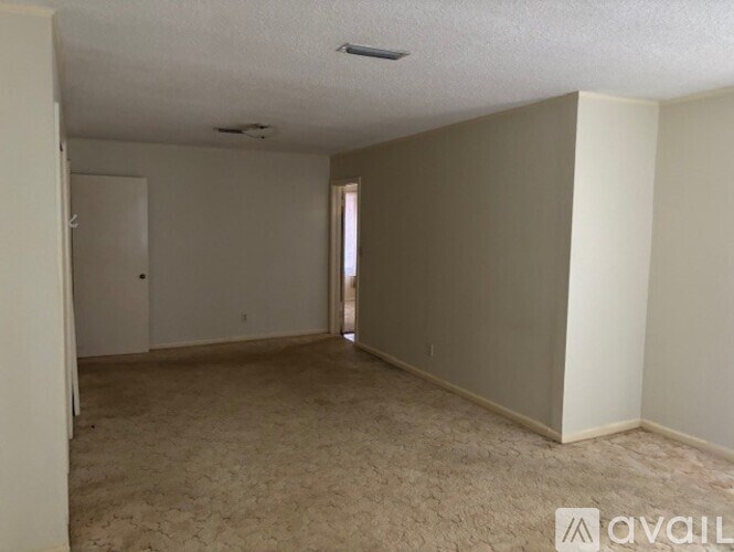 A room with beige carpeting and white walls is available for rent.