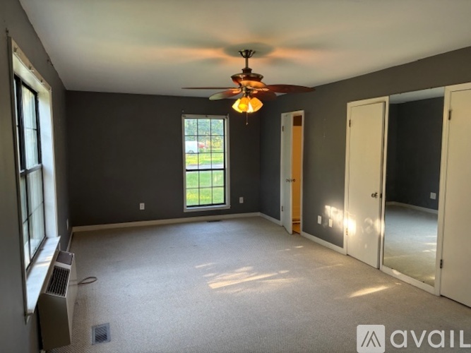 A room with a ceiling fan and a window overlooking a yard.
