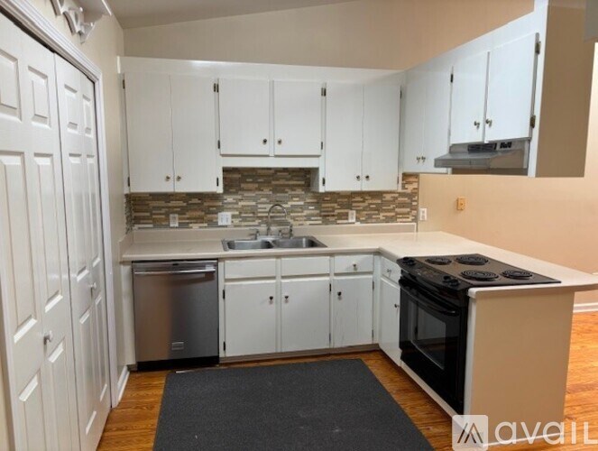 A kitchen with white cabinets and a stone backsplash.