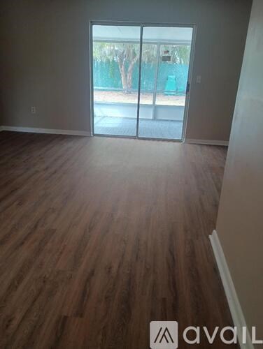 A room with wooden flooring and a sliding glass door.