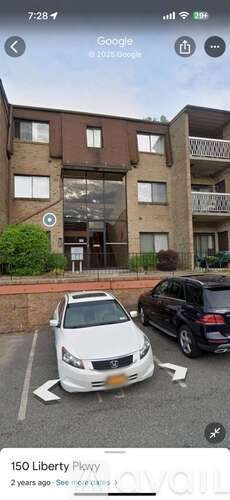A white car is parked in a parking lot in front of a building.