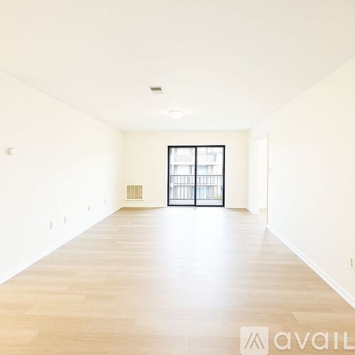 A spacious room with wooden flooring and a sliding glass door.