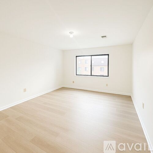 A spacious room with wooden flooring and a window.
