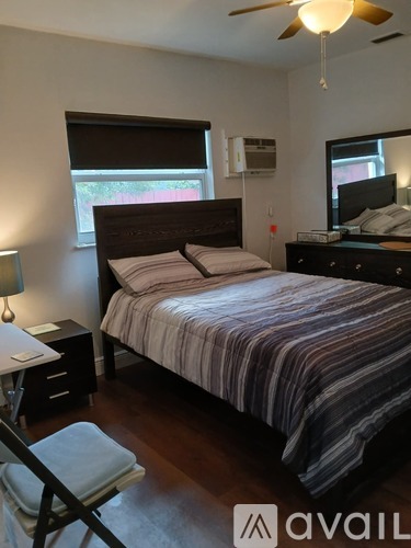 A bedroom with a bed, nightstand, and window.