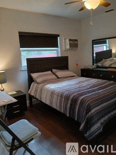 A bedroom with a bed, nightstand, and window.