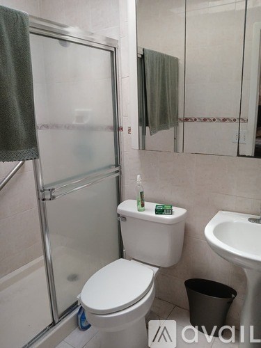 A white toilet with a green towel and a bottle of hand soap on top of it.