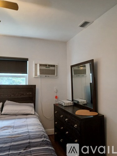 A bedroom with a bed, dresser, and mirror.