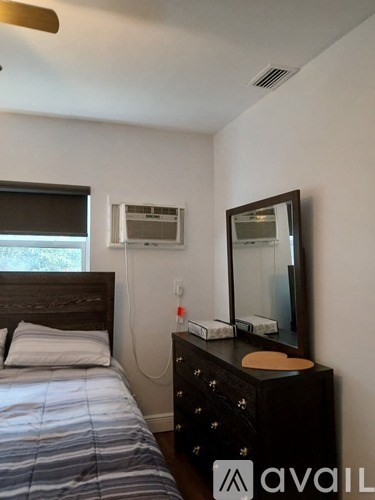 A bedroom with a bed, dresser, and mirror.