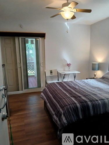 A bedroom with a bed, a chair, and a ceiling fan.