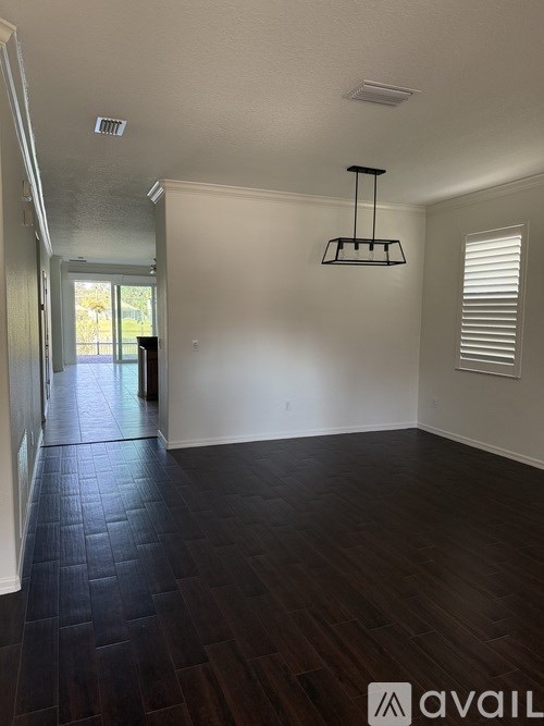 A room with dark wood flooring and a hanging light fixture.