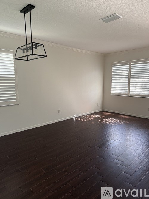 A room with wooden flooring and a hanging light fixture.