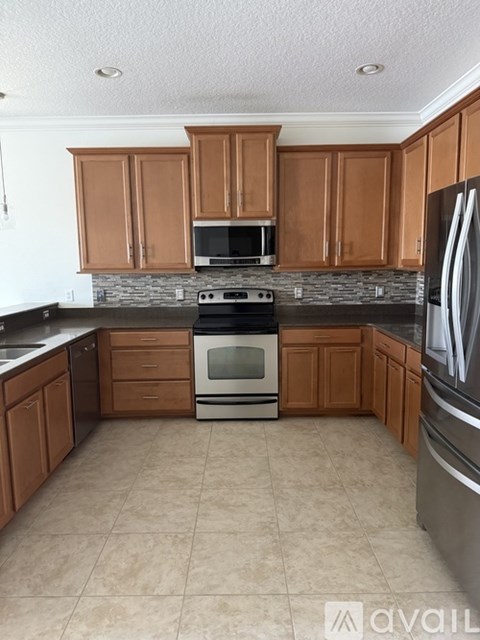 A kitchen with brown cabinets and a black fridge.
