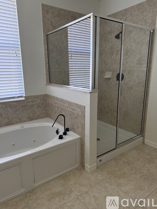 A bathroom with a white tub and a glass shower stall.