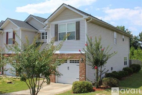 A house with a garage and a tree in front.