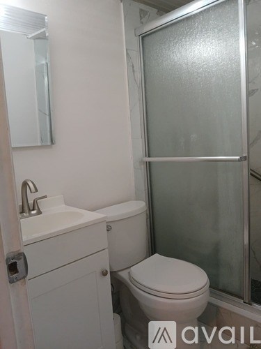 A white toilet sits in a bathroom next to a sink and a glass shower door.