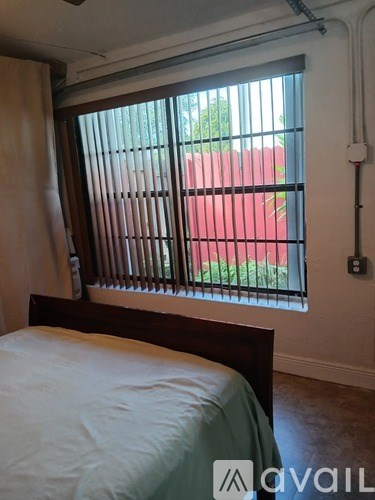 A bedroom with a bed and a window with blinds.