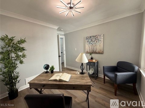 A living room with a wooden table, a blue chair, and a painting on the wall.