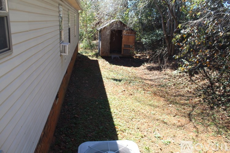 A white house with a brown shed in the backyard.