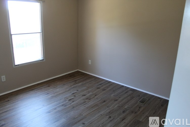 A room with wooden flooring and a window letting in light.