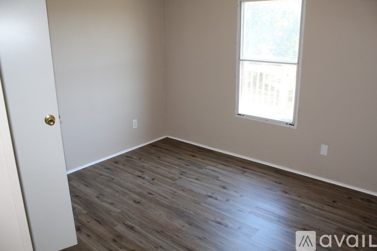 A room with a wooden floor and a window letting in light.