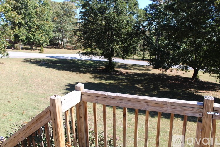 A wooden fence in front of a grassy area with trees in the background.