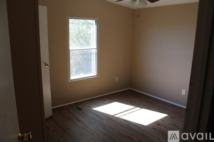 A room with a window and wooden floors is available for rent.