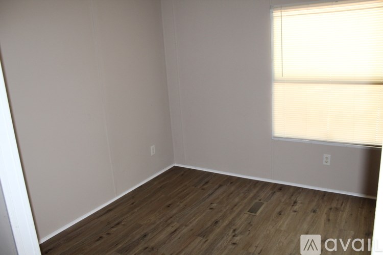 A room with wooden flooring and a window with blinds.