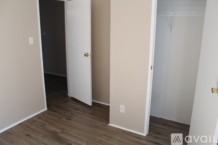 A room with a white door and a wooden floor.
