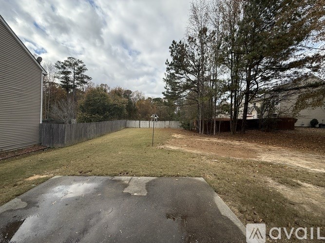 A backyard with a concrete slab and a fence.