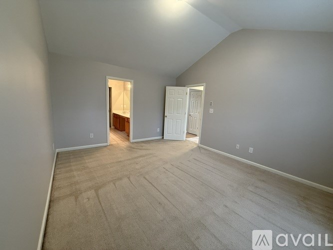 A room with a carpeted floor and two doors, one of which is open.