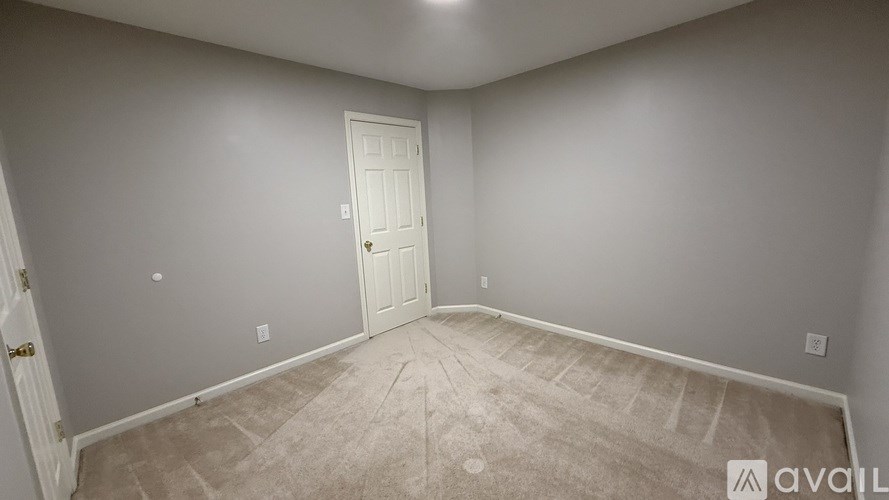 A room with a door and a carpeted floor.