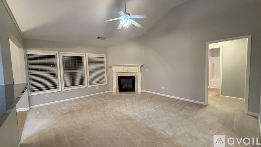 A spacious living room with a fireplace and a ceiling fan.
