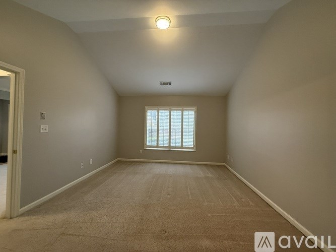 A spacious room with a window and carpeted floor.