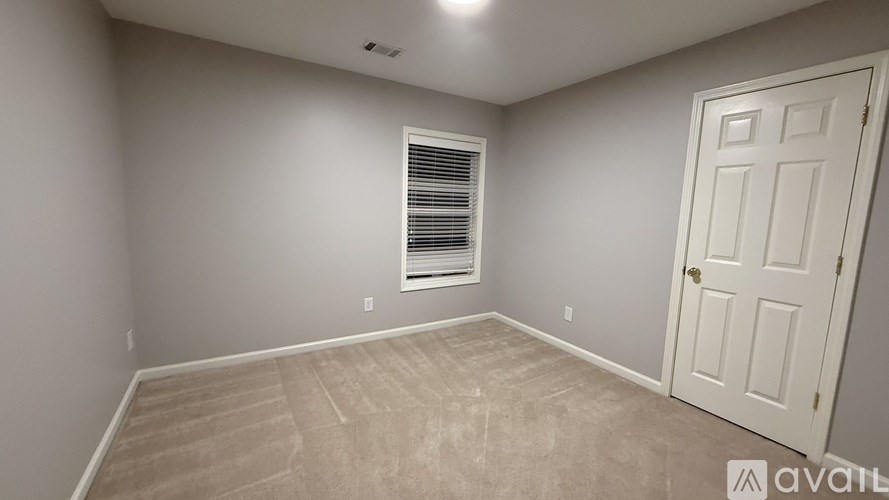 A room with a door and a window with blinds.