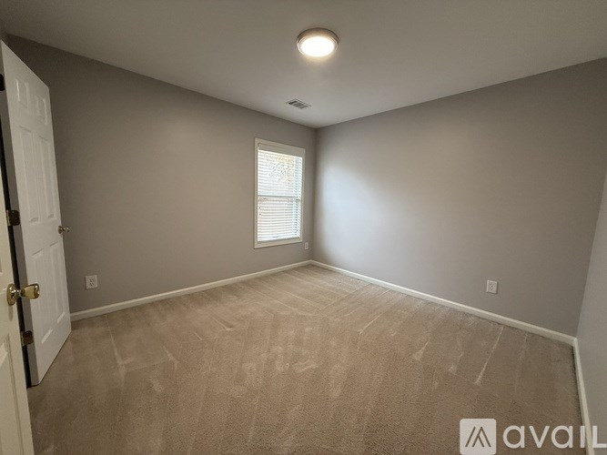A room with a carpeted floor and a door on the left side.