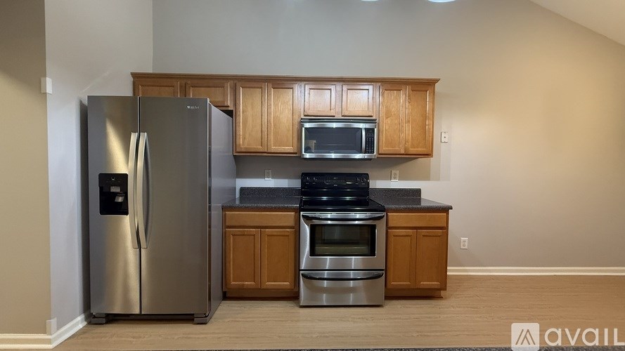 A kitchen with a stainless steel refrigerator, microwave, oven, and cabinets.