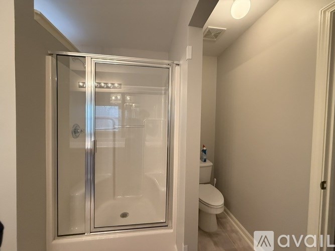 A bathroom with a glass shower door and a toilet.
