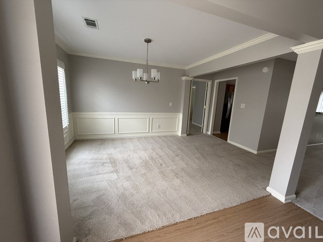 A room with a carpeted floor and a chandelier hanging from the ceiling.