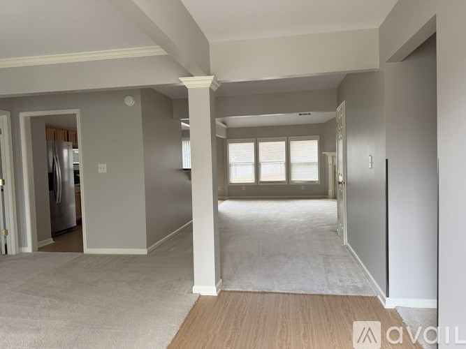 A spacious living room with a kitchen in the background.