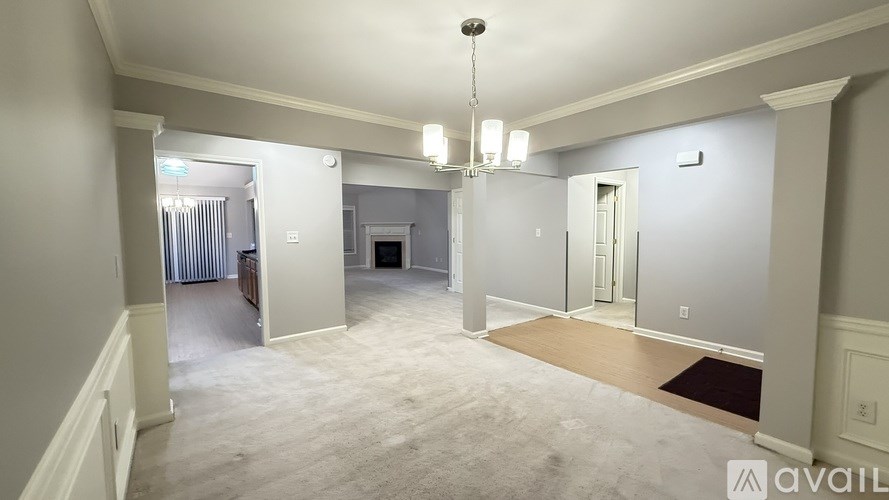 A spacious room with a chandelier and a rug on the floor.