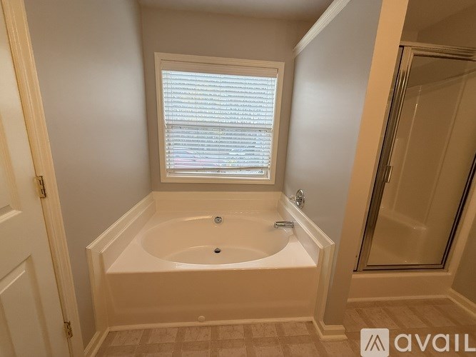 A bathroom with a bathtub and a window with blinds.