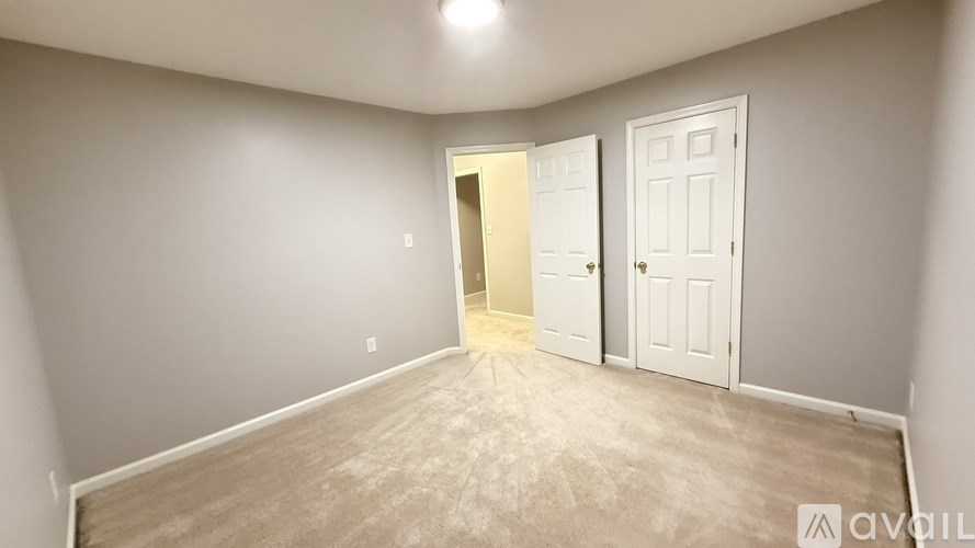 A room with a carpeted floor and two doors, one of which is open.