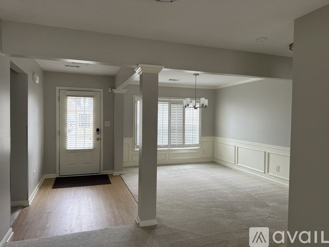 A spacious room with a door, windows, and a carpeted floor.