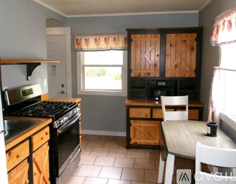 A kitchen with a black stove top oven and wooden cabinets.