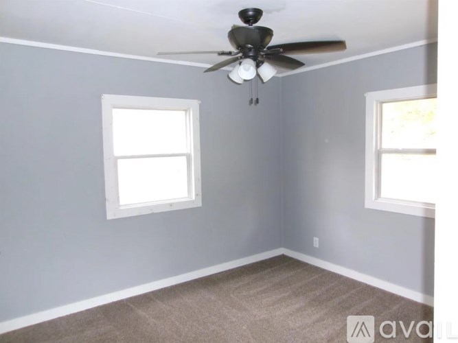 A room with a ceiling fan and two windows.