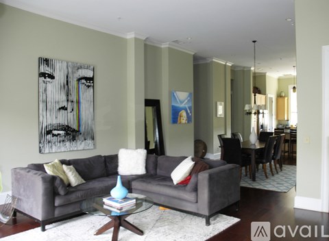 A living room with a grey couch and a painting on the wall.